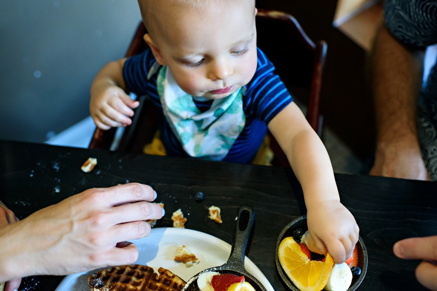A baby reaching for some fruit.